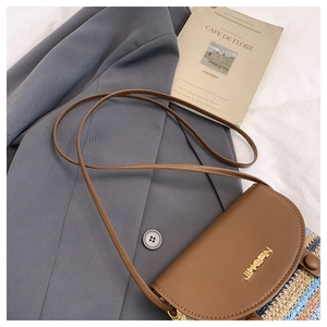 Detail of vintage crossbody bag showing brown leather flap and colorful woven texture