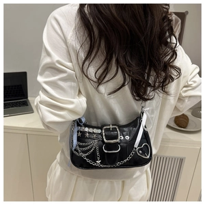 Detail of black leather shoulder bag with silver chains, star studs and blue plaid ribbon