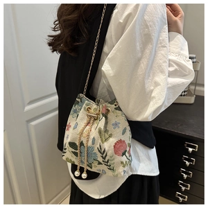 Detail of floral jacquard bucket bag with pearl drawstring and golden chain strap