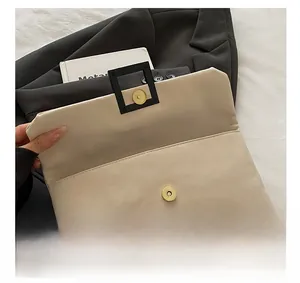 Detail view of cream leather envelope bag showing magnetic closure and metal square buckle