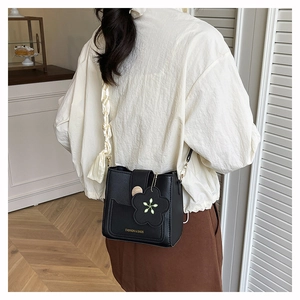 Detail der schwarzen Eimertasche aus Leder mit Seidenband und Blumenanhänger