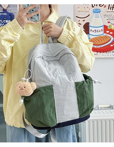 Detail of color-block nylon backpack with drawstring side pocket and plush bear charm