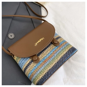 Detail of colorful woven shoulder bag featuring a brown leather flap with metal logo