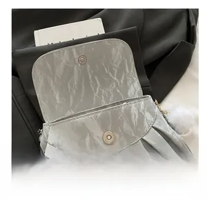 Close-up of silver pleated crossbody bag featuring a magnetic metal buckle closure