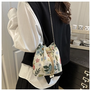 Close-up of ethnic jacquard bucket bag with floral embroidery and pearl drawstring detail