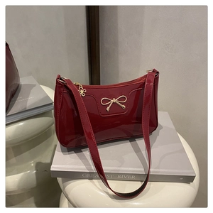 Dettaglio di una borsa baguette in pelle verniciata rosso scuro con fibbia dorata
