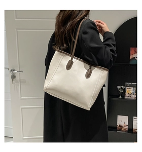 Model wearing a minimalist cream leather tote bag with dark brown straps for daily commute