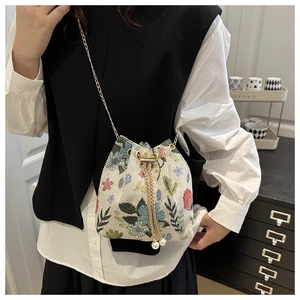 Détail du sac seau en jacquard floral avec cordon perlé et bandoulière dorée
