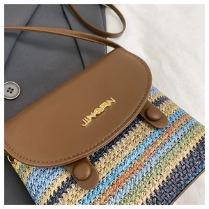 Detail of colorful striped woven straw bag with premium brown leather flap and metal logo