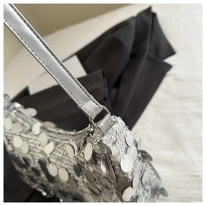 Dettaglio di paillettes argentate e hardware metallico su una borsa a tracolla chic