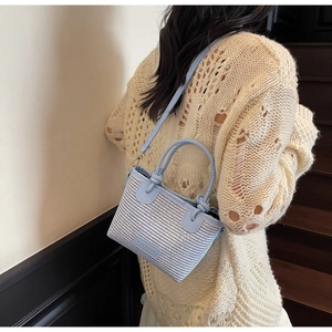 Detail of woven straw bag with blue leather handles and fashion label for women