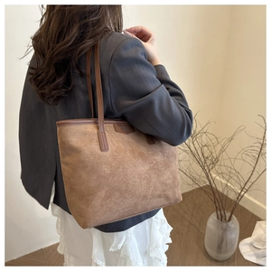 Close-up of brown suede leather tote bag texture with minimalist embossed logo detail