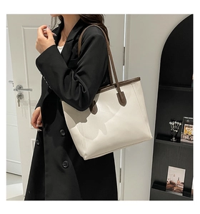 Detail of minimalist cream tote bag with dark brown handles for elegant office commute