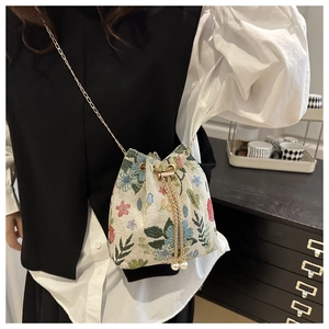 Détail d'un sac seau floral en tapisserie avec broderies et bandoulière chaîne dorée