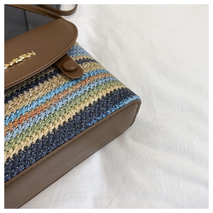 Gros plan d'un sac en paille à rayures colorées avec rabat en cuir brun et logo doré