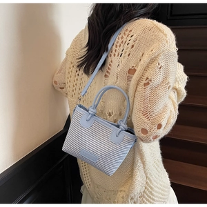 Detail of light blue woven bucket bag showing fine texture and adjustable shoulder strap