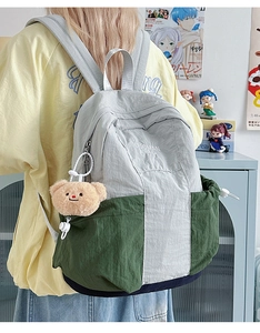 Detailed view of the tricolor nylon backpack featuring a bear charm and brand logo