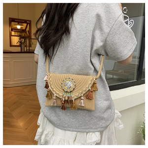 Detail of bohemian straw crossbody bag with ethnic tassels and colorful bead accents