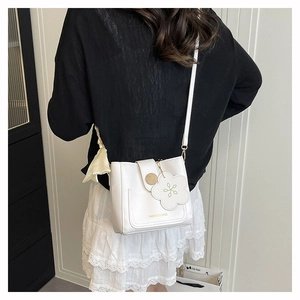 Detailansicht einer weißen PU-Leder Eimertasche mit Golddruck und Blumenanhänger