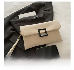 Detail of beige envelope clutch with black buckle and wrist strap on a black blazer