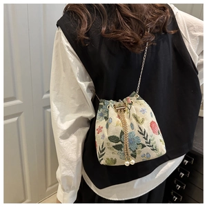 Detailed close-up of floral embroidery texture and pearl drawstring on bucket bag