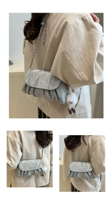 Detail of silver pleated chain bag featuring fashion text and a white plush charm
