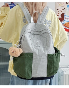 Close-up of color-block nylon backpack with plush bear charm and embroidery detail