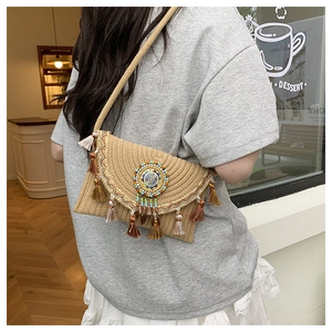 Detail of straw envelope bag featuring bohemian tassels and colorful beaded mandala