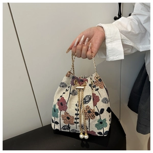 Détail du sac seau tissé en tissu jacquard fleuri avec charms de cordon en perles