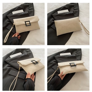 Detail view of cream rectangle envelope clutch bag with black square buckle and wristlet