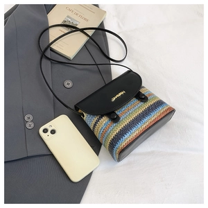 Détail du sac en paille tissé à rayures avec rabat en cuir noir et logo en métal