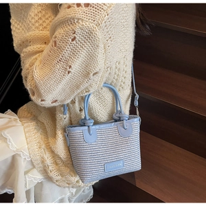 Detail of blue and white woven bucket bag with leather trim and adjustable shoulder strap