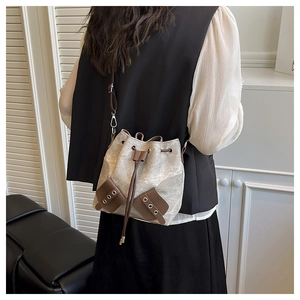 Model carrying a vintage-style drawstring bucket bag with side pockets and silver hardware