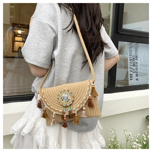 Detail of bohemian straw crossbody bag featuring colorful tassels and beadwork embroidery
