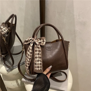 Dark brown leather bucket bag with silk scarf accent and crossbody strap for daily commute