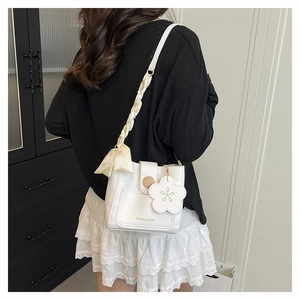 Detail of cream crossbody bag with silk scarf woven strap and floral pendant decoration