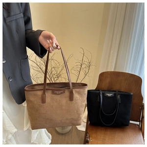 Close-up of brown and black suede tote bags with FANYISSA BAGS logo on a vintage chair