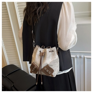 Detail of drawstring bucket bag made of canvas and brown leather on model