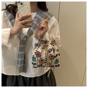 Détail du sac seau en lin fleuri avec cordon perlé et poignée en chaîne dorée