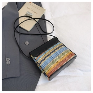 Détail du sac en paille tissée à rayures avec rabat en similicuir noir et fine bandoulière