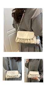 Detail view of cream pleated crossbody bag with chain strap and plush pendant