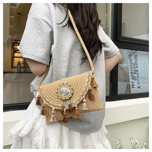 Detail of bohemian straw crossbody bag with colorful bead charms and tassel accents