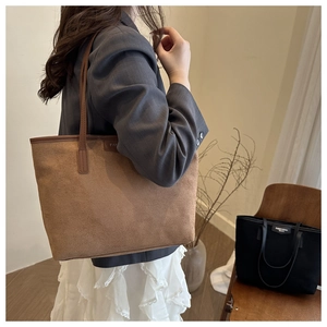 Close-up of a large brown matte suede tote bag worn on a model's shoulder for commuting
