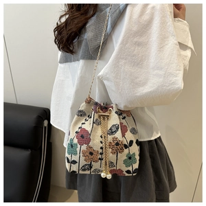 Détail du sac seau en tricot ethnique avec broderies florales et glands de perles de serrage