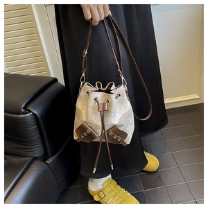 Close-up of canvas bucket bag with brown leather trim and metal rivet details