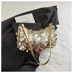 Dettaglio di paillettes dorate su una borsa sottobraccio elegante con finitura metallica