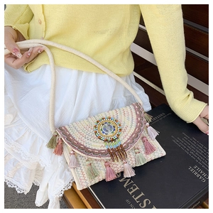 Detail of bohemian straw bag featuring colorful geometric embroidery and beaded fringe