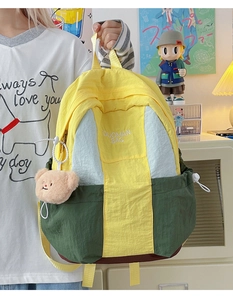 Detail of color-block nylon backpack with bear pendant in a cozy student room setting