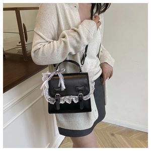 Detail of crossbody bag featuring lace trim and a pink checkered ribbon on the handle