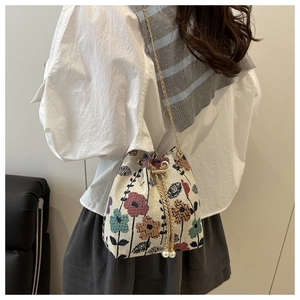 Détail du sac seau en tissu jacquard fleuri avec cordon perlé et bandoulière chaîne
